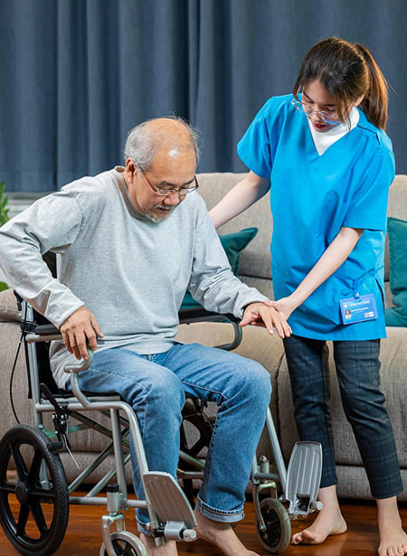 Nurse assisting an elderly patient from a wheelchair